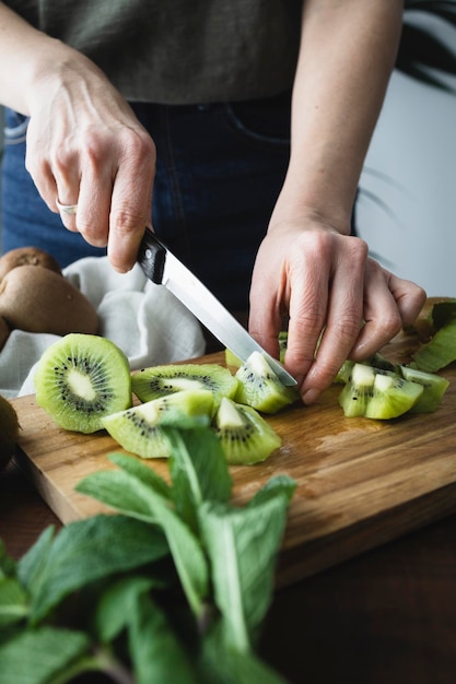 Mulher na cozinha cortando kiwis Menina preparando frutas frescas e suculentas