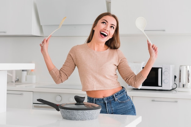 Foto mulher na cozinha segurando conchas