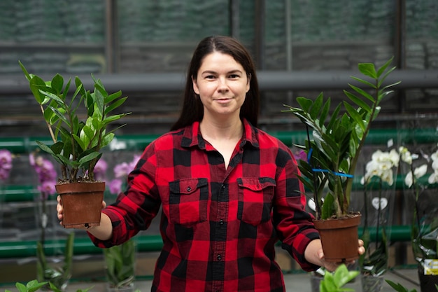 Mulher na estufa fazendo escolha entre duas plantas em vasosConceito de escolher plantas domésticas