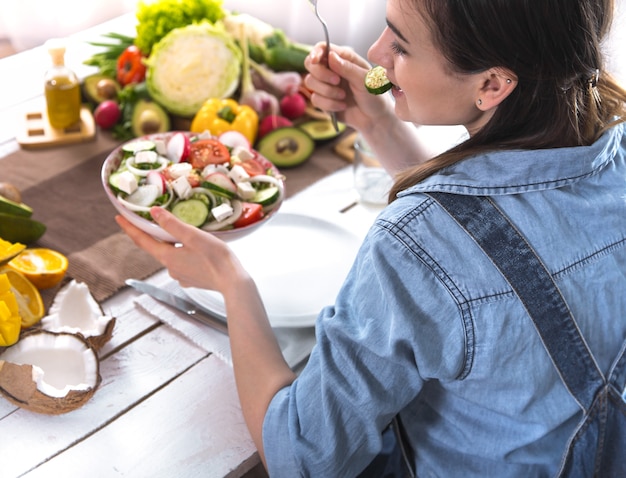 Foto mulher na mesa de jantar, comendo salada, vista superior.