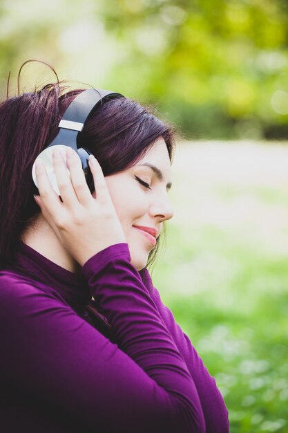 Mulher na música de escuta do parque com fones de ouvido.