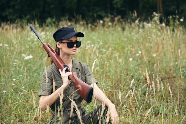 Mulher na natureza Óculos de sol com braços no ombro abrigando-se na grama armas árvores verdes no fundo