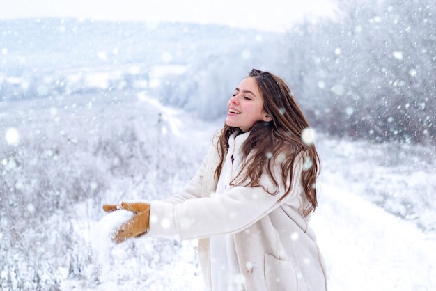 Mulher na neve jogo de bola de neve brincando com neve e se divertindo no parque de inverno atividade sorrindo garota em