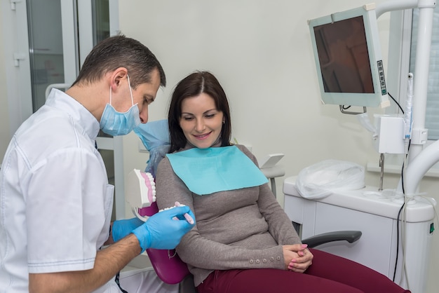 Mulher na odontologia apontando para amostrador de dentes