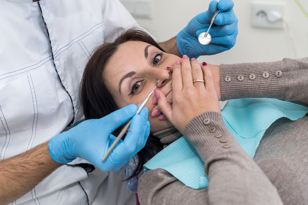 Mulher na odontologia fechando a boca com as mãos