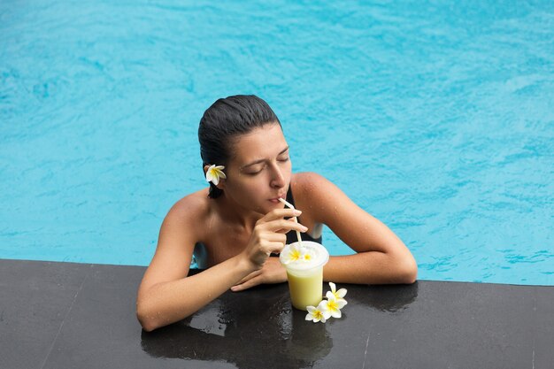 Mulher na piscina com bebida de frutas