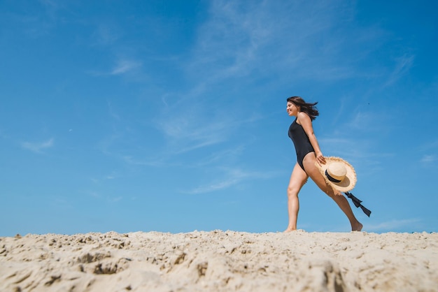 Mulher na praia de areia no céu azul de maiô preto no fundo