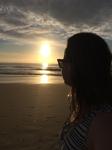 Foto mulher na praia durante o pôr-do-sol