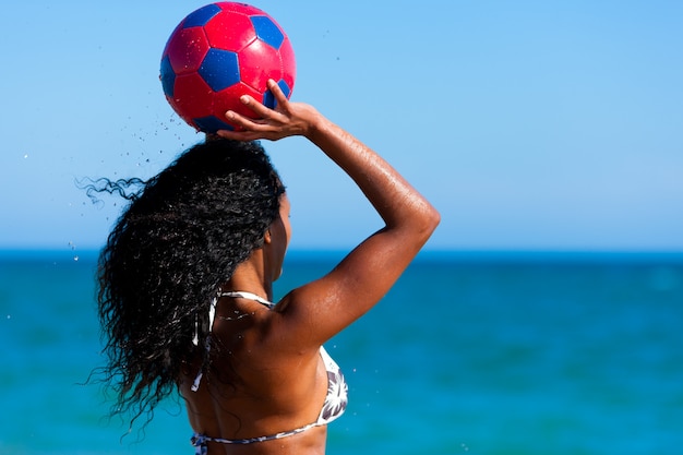 Mulher na praia jogando futebol