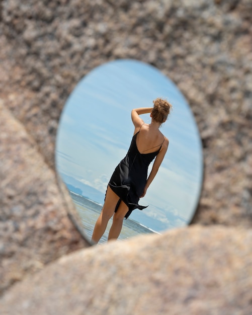 Mulher na praia no verão posando com espelho redondo