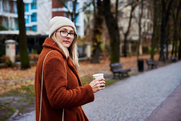 Mulher na rua da cidade com uma xícara de café