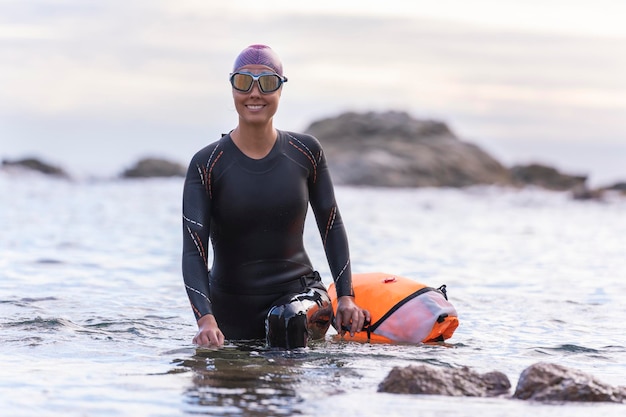 Mulher nadando em águas abertas com roupa de neoprene e bóia