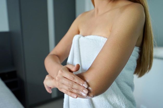 Mulher não identificada aplicando creme corporal em seu cotovelo Loção corporal creme hidratante proteção solar conceito de cosméticos