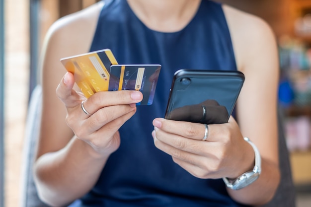 Mulher negócio, segurando, cartão crédito, e, usando, smartphone