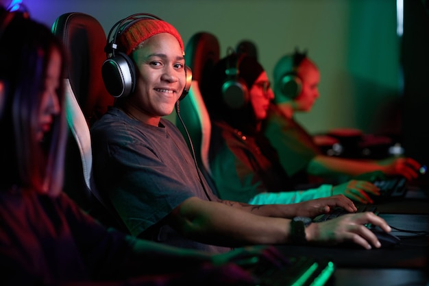 Mulher negra a jogar videogames e a sorrir para a câmara.