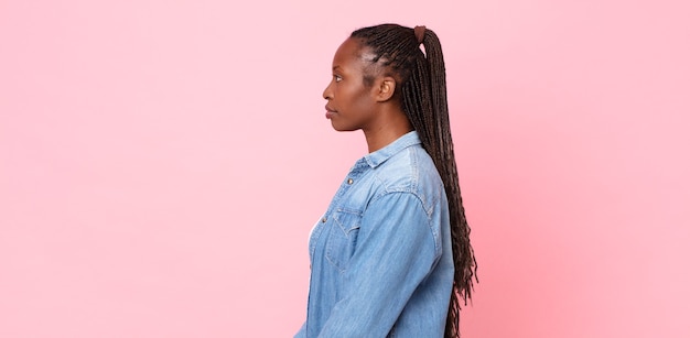 Mulher negra adulta afro em vista de perfil olhando para copiar o espaço à frente, pensando, imaginando ou sonhando acordada