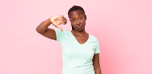 Mulher negra adulta negra se sentindo zangada, irritada, desapontada ou descontente, mostrando o polegar para baixo com um olhar sério