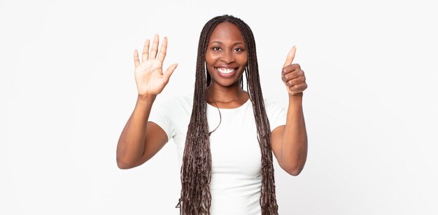 Mulher negra adulta negra sorrindo e parecendo amigável, mostrando o número seis ou sexto com a mão para a frente, em contagem regressiva