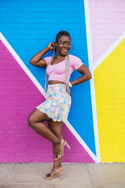 Mulher negra africana muito feliz posando em uma parede em várias cores. Foto de estilo de vida de uma mulher africana feliz