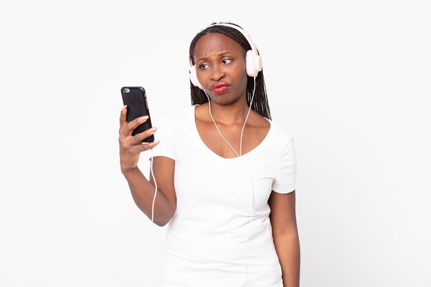 Mulher negra afro-americana adulta ouvindo música com fones de ouvido e smartphone