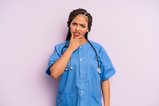 Mulher negra afro com boca e olhos bem abertos e mão no queixo. conceito de enfermeira