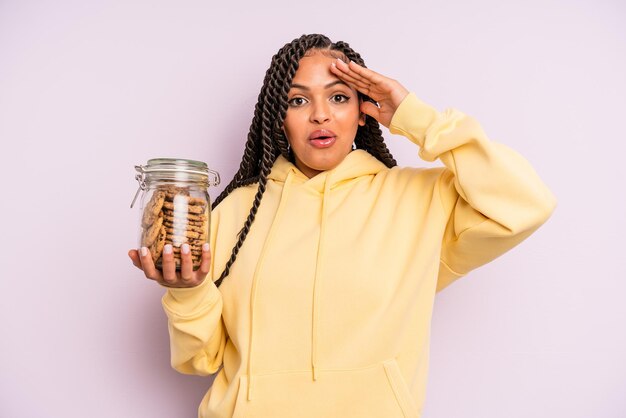 Mulher negra afro olhando feliz conceito de biscoitos surpresos e surpresos