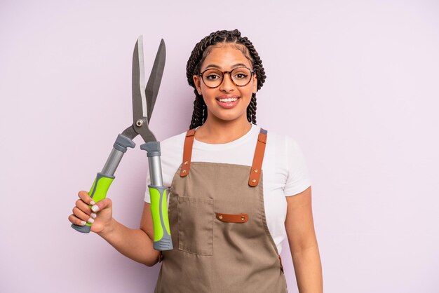 Mulher negra afro olhando feliz e agradavelmente surpreso. conceito de jardineiro ou agricultor