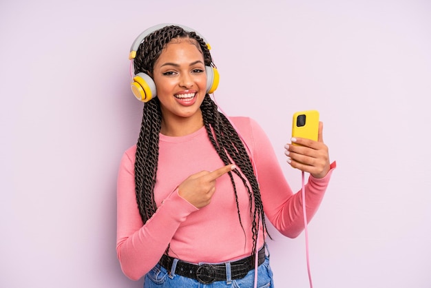 Mulher negra afro parecendo animada e surpresa apontando para o lado ouvindo o conceito de música