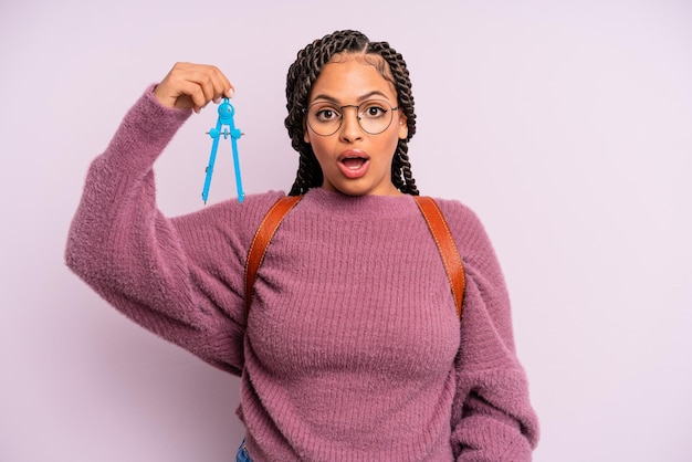 Mulher negra afro parecendo muito chocada ou surpresa. medir o conceito de estudante de bússola