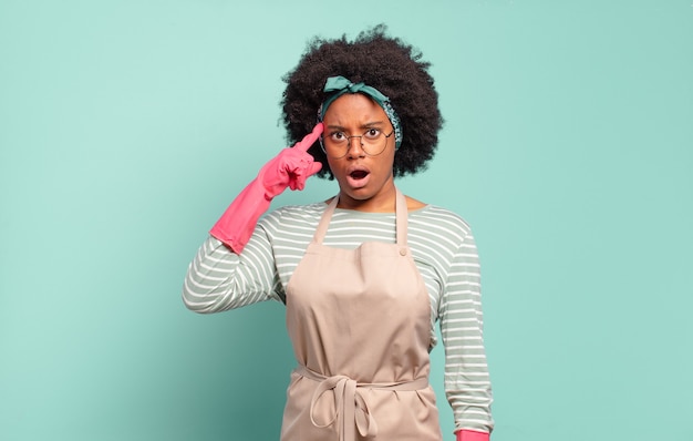 Mulher negra afro parecendo surpresa, boquiaberta, chocada, percebendo um novo pensamento, ideia ou conceito. conceito de limpeza