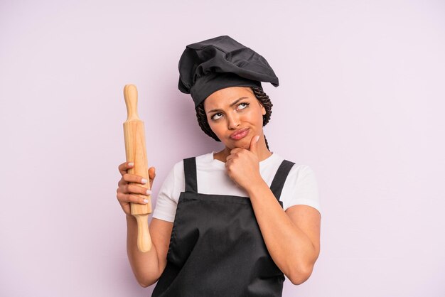 Mulher negra afro pensando se sentindo chef duvidoso e confuso com um pino de rolo