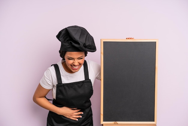 mulher negra afro rindo alto de alguma piada hilária. conceito de chef e quadro-negro