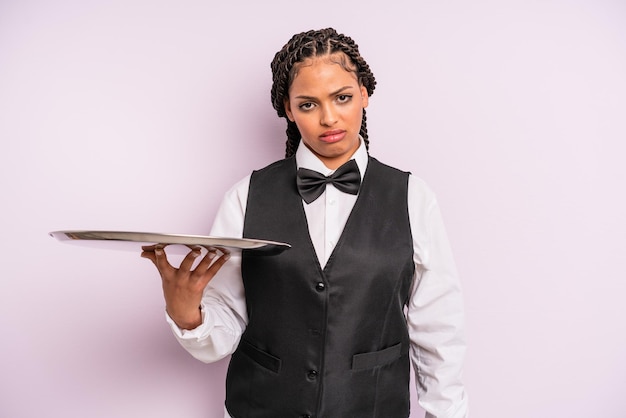 Mulher negra afro se sentindo confuso e confuso garçom com uma bandeja