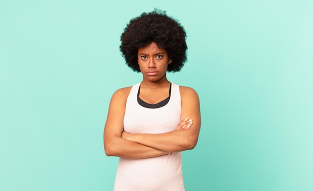 Mulher negra afro se sentindo descontente e decepcionada, parecendo séria, irritada e com raiva de braços cruzados