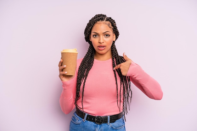 Mulher negra afro se sentindo feliz e apontando para si mesma com um animado café para viagem
