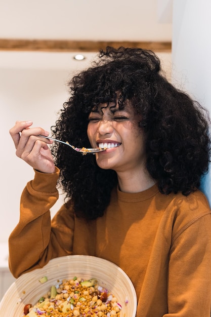 Mulher negra alegre a comer salada saudável.