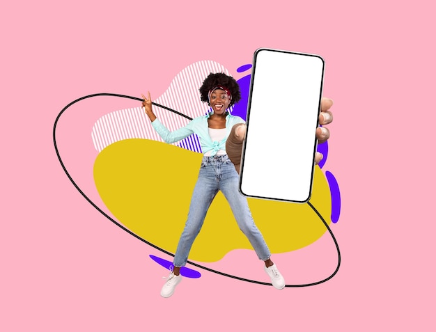 Mulher negra alegre a saltar com um grande smartphone em branco na mão.