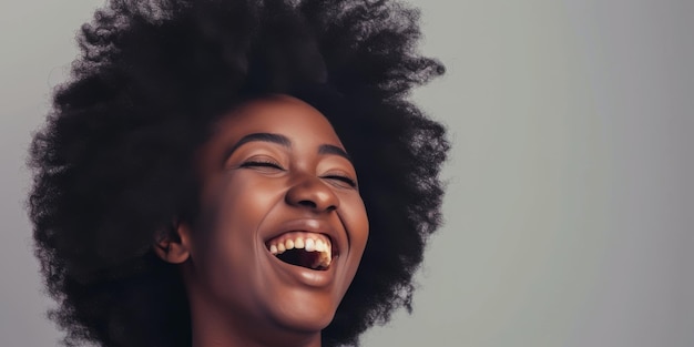 Mulher negra alegre ri no estúdio contra um fundo cinzento subtil.