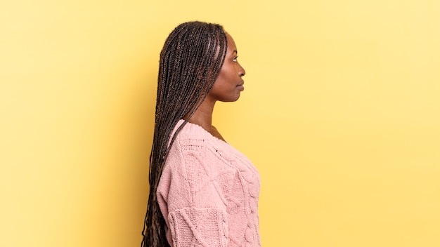 mulher negra bonita afro em vista de perfil olhando para copiar o espaço à frente, pensando, imaginando ou sonhando acordado