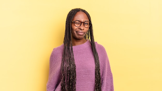 Mulher negra bonita, afro, parecendo feliz e amigável, sorrindo e piscando os olhos para você com uma atitude positiva