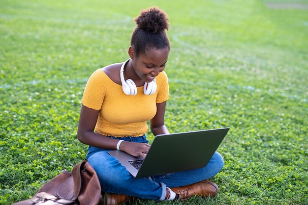 Mulher negra bonita estudando no parque de sua aluna da cidade preparando o conceito de pesquisa ao ar livre de conexão com a internet e trabalho remoto