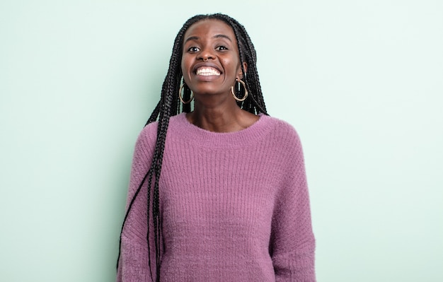 Mulher negra bonita parecendo feliz e boba com um sorriso largo, divertido e maluco e olhos bem abertos