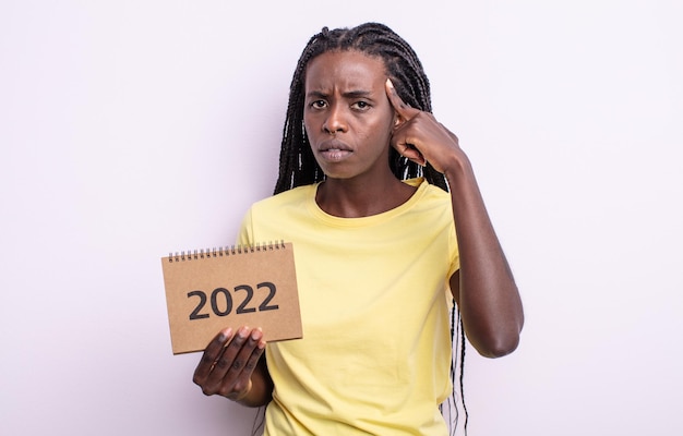 Mulher negra bonita se sentindo confusa e confusa, mostrando que você é insana. conceito de calendário 2022