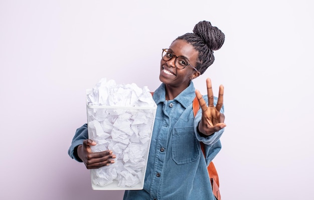 Mulher negra bonita sorrindo e parecendo amigável, mostrando o número três. conceito de falha de bolas de papel