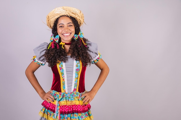 Foto mulher negra brasileira vestindo roupas de festa junina confraternização em nome de são joão arraial mãos na cintura