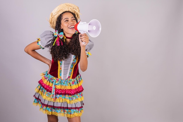 Mulher negra brasileira vestindo roupas de festa junina confraternização em nome de São João Arraial Promoção de gritos com megafone