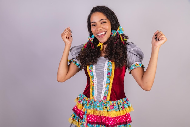 Mulher negra brasileira vestindo roupas de festa junina confraternização em nome do acampamento de São João comemorando