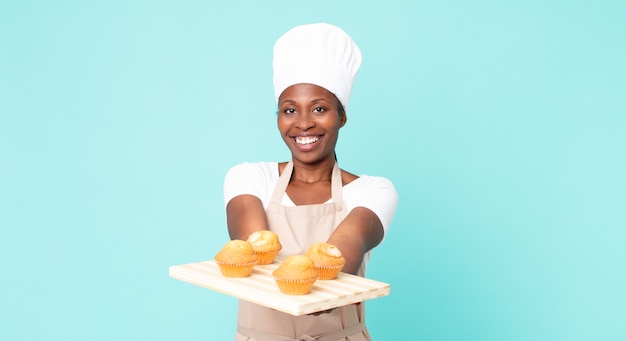 Mulher negra chef adulta afro-americana segurando uma bandeja de muffins