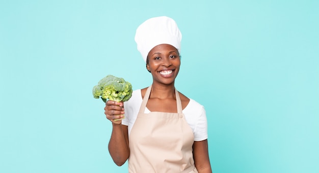 Mulher negra chef adulta segurando um brócolis