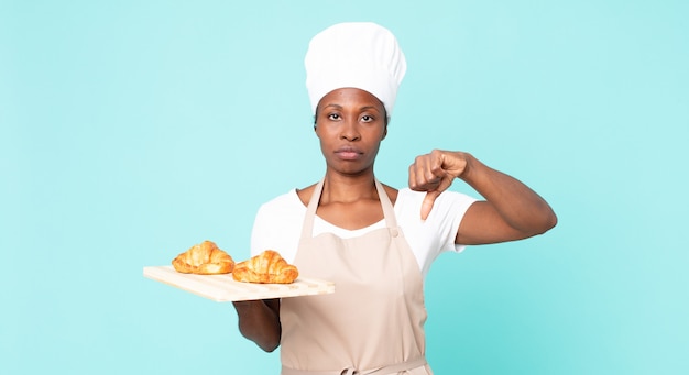 Mulher negra chef adulta segurando uma bandeja de croissants